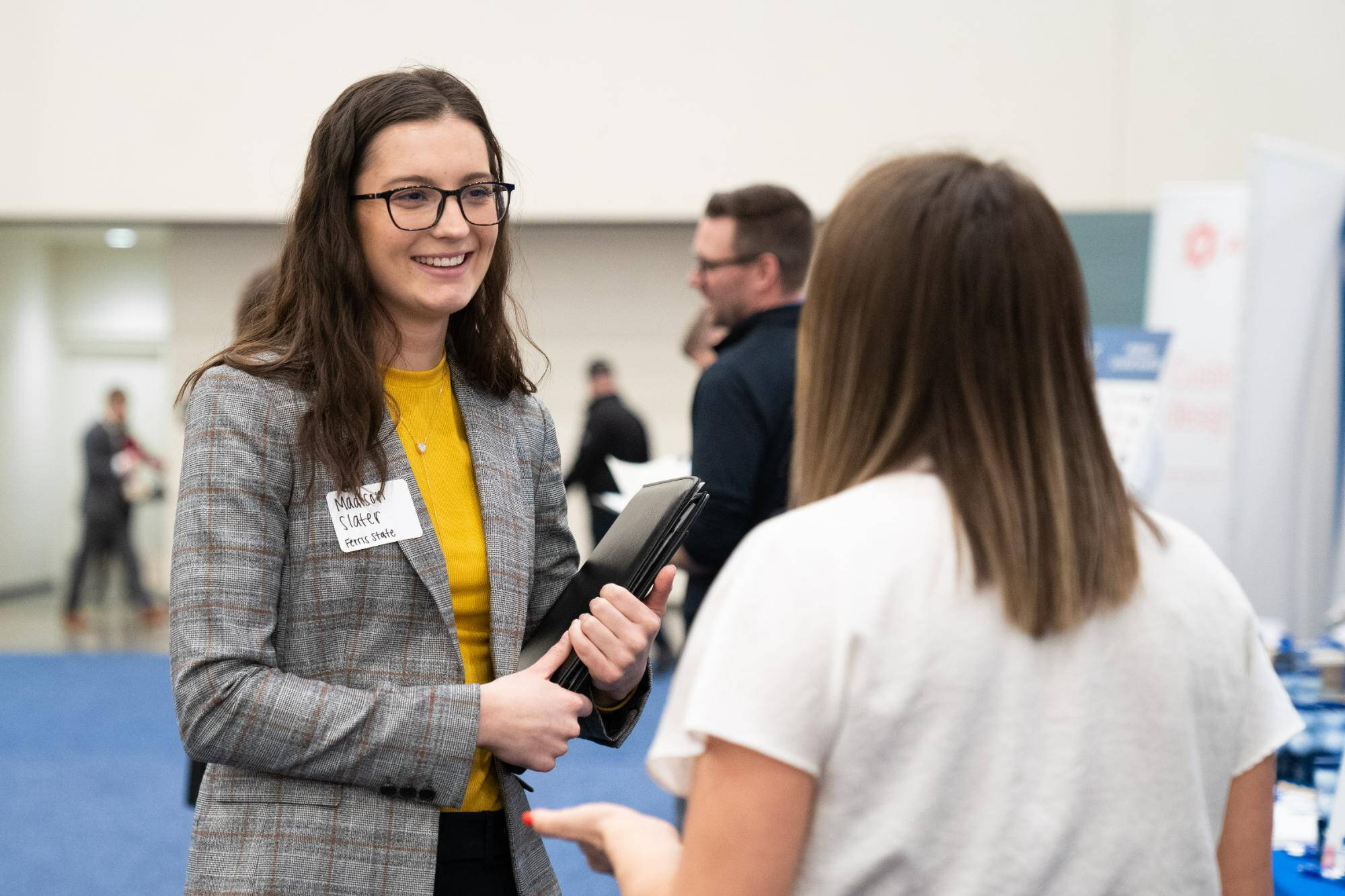 Person holding a binder talking to another person